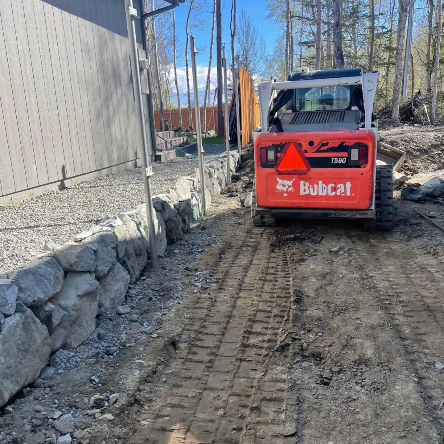 Bobcat grading at a rock wall install in progress — Blackstone Landscaping AK